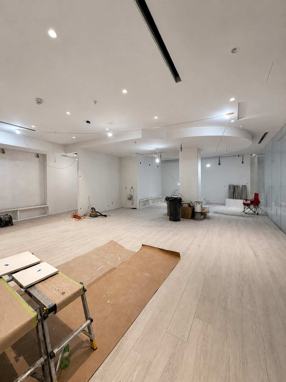 Shifeon commercial interior during flooring and lighting installation with tools and temporary work lights in place.